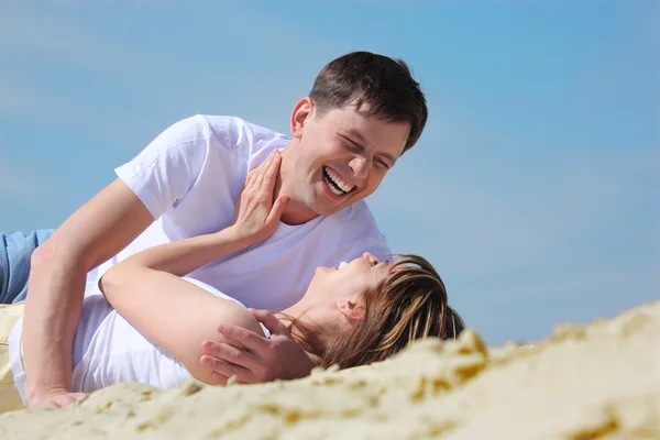 Rindo jovem par deitado na areia — Fotografia de Stock