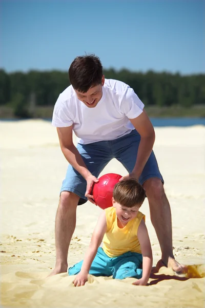 Padre con figlio giocare con palla sulla sabbia — Foto Stock