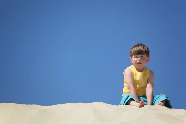 Niño se sienta en la arena — Foto de Stock