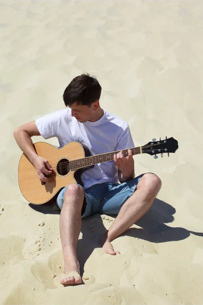 Mann spielt Gitarre im Sitzen auf Sand — Stockfoto