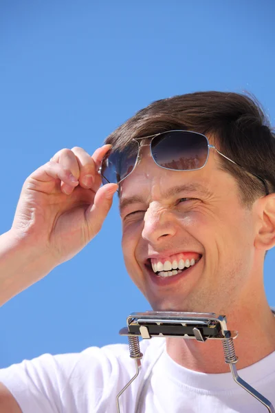 Smějící se muž s rtu akordeon a sluneční brýle — Stock fotografie