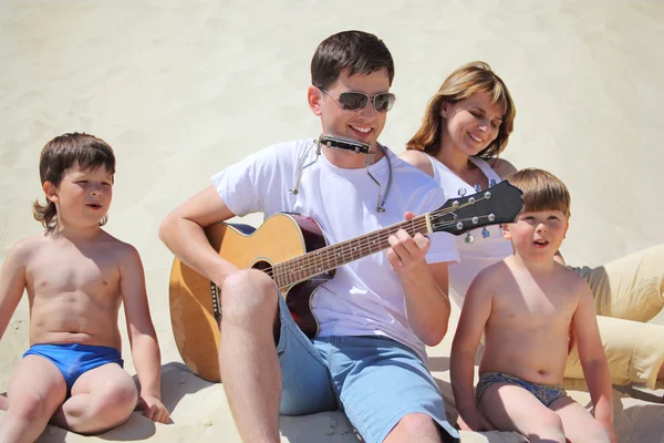 Guy aux lunettes de soleil joue de la guitare et de l'accordéon à lèvres avec des enfants — Photo