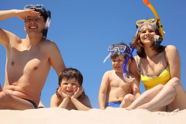 Os pais com crianças em máscaras subaquáticas sentam-se na areia — Fotografia de Stock