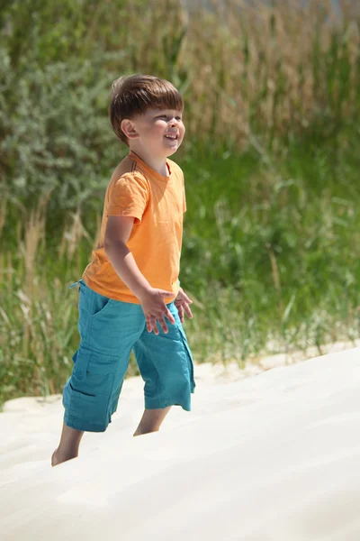 Мальчик идет по песку, вид сбоку — стоковое фото