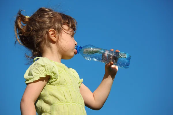 Menina bebe água de garrafa de plástico contra o céu azul — Fotografia de Stock