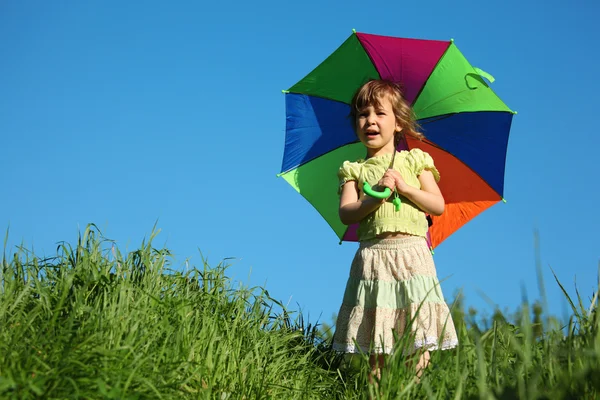 Девушка с разноцветным зонтиком в траве — стоковое фото