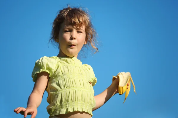 Девушка ест банан на голубом небе — стоковое фото