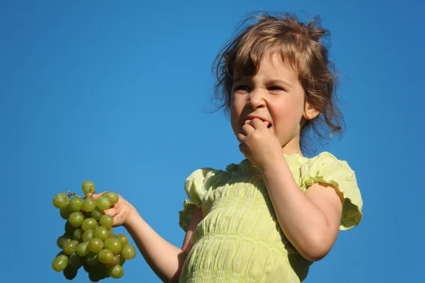 Lány eszik szőlő kék ég ellen — Stock Fotó