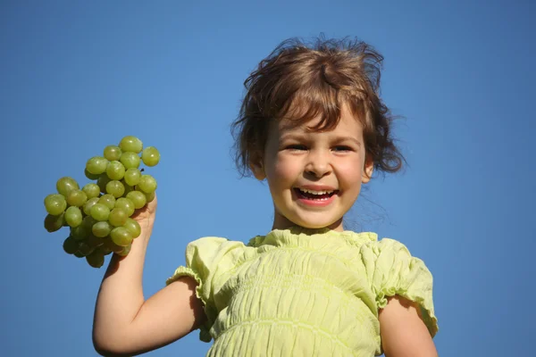 Fille souriante avec raisin contre le ciel bleu — Photo