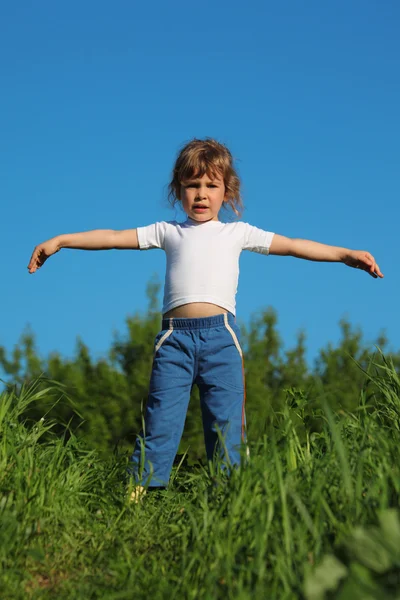 Klein meisje maakt gymnastische in gras — Stockfoto