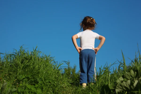 Liten flicka gör gymnastik i gräs, bakifrån — Stockfoto