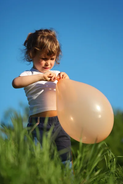 Маленькая девочка с воздушным шаром в траве — стоковое фото