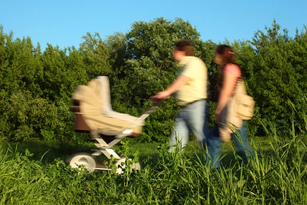 Par com carruagem infantil em movimento no parque — Fotografia de Stock