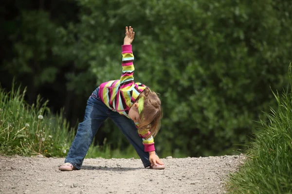 Klein meisje maakt gymnastische in park — Stockfoto