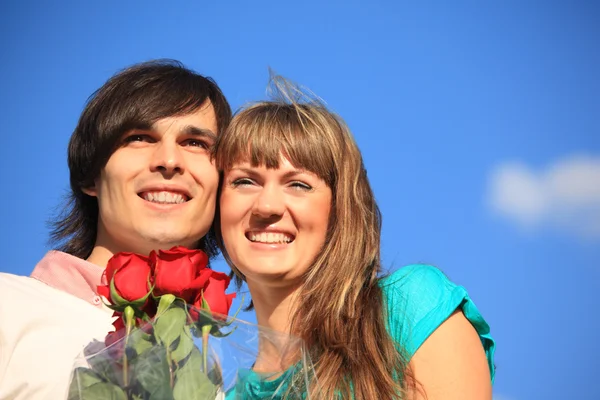 Jonge paar met boeket rozen tegen hemel — Stockfoto