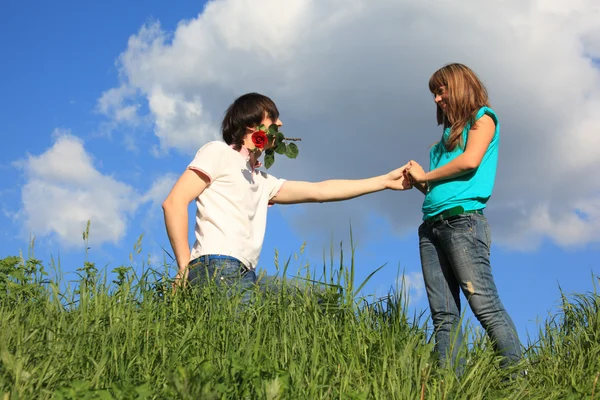 Guy with rose in mouth and girl in grass — Stock Photo, Image