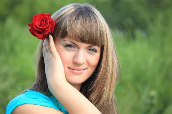 Meisje met rode roos in haar — Stockfoto