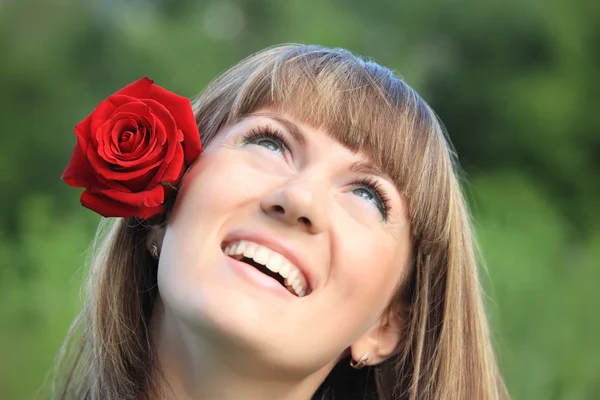 Dziewczyna z czerwoną różą we włosach wygląda w górę — Zdjęcie stockowe