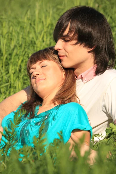 Девушка лежит на парне, сидящем в траве — стоковое фото