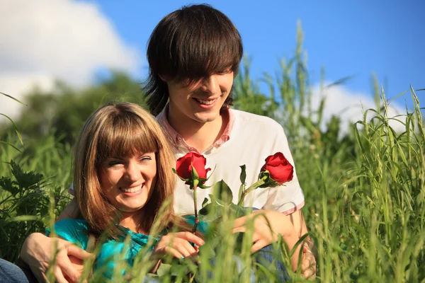 Jovem par com rosas na grama — Fotografia de Stock