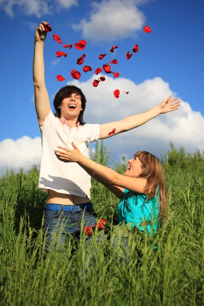 Young pair scatters petals of roses in grass — Stock Photo, Image