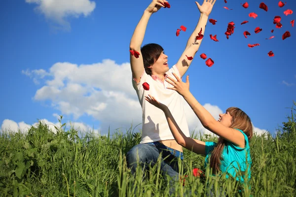 Young pair scatters petals of roses in grass — Stock Photo, Image