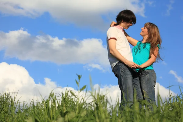 Mladá dvojice vzájemně drží v trávě proti obloze — Stock fotografie