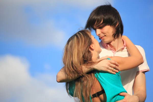 Joven pareja abraza contra el cielo — Foto de Stock