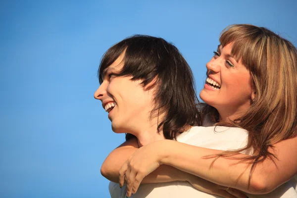 Girl embraces guy behind for neck against sky — Stock Photo, Image