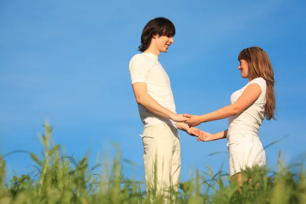 Девушка и парень стоят на траве, взявшись за руки — стоковое фото