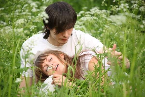 Menina encontra-se no colo do cara sentado na grama — Fotografia de Stock