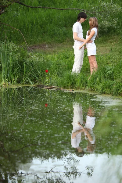 Mladá dvojice stojí na břehu rybníka — Stock fotografie