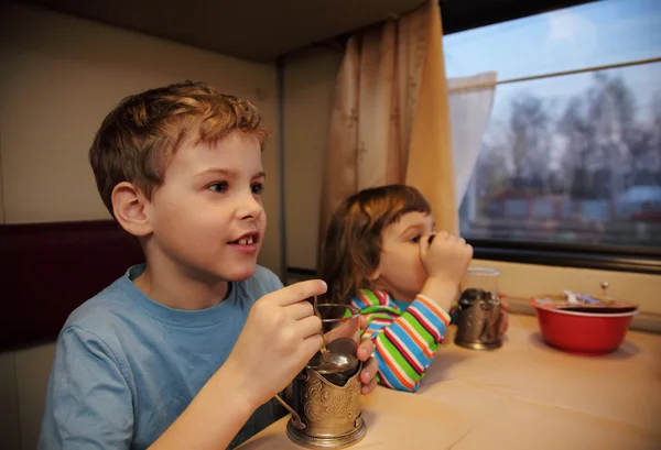 Two children drink tea from glasses in train car — Stok fotoğraf