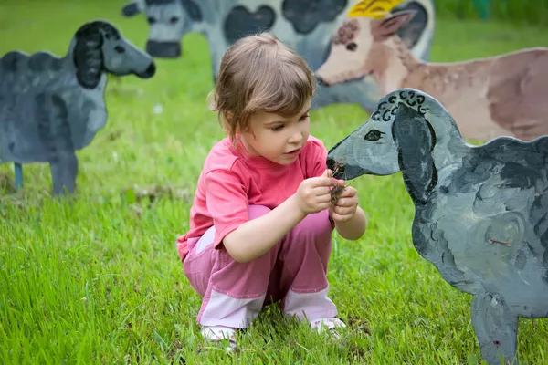 La niña y el niño alimentan a un animal de madera —  Fotos de Stock