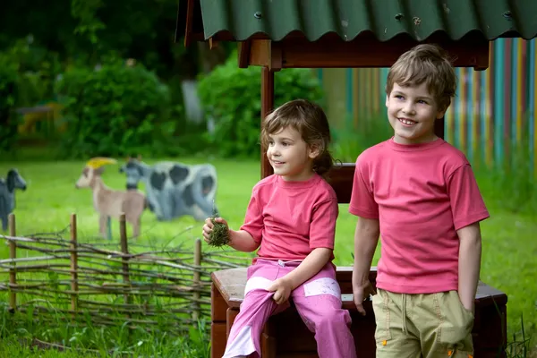 The girl and the boy sit on a well — Stock Photo, Image