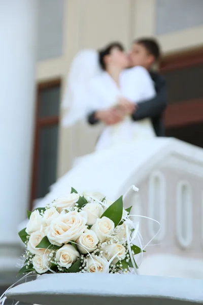 Bouquet and newly married couple kissing — Stock Photo, Image