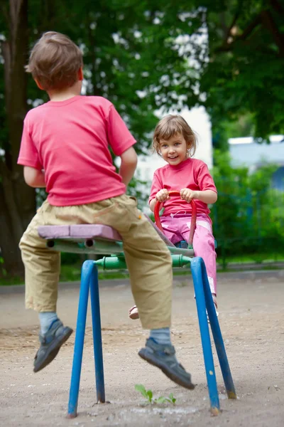 Мальчик и девочка на качелях в парке — стоковое фото