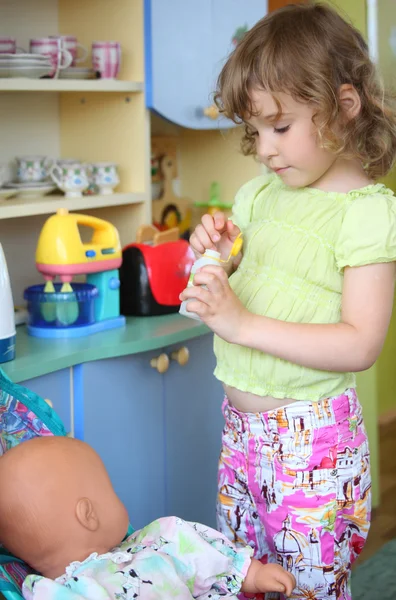 Little girl plays with doll on kitchen — Stock Photo, Image