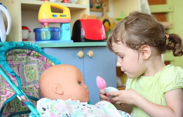 Little girl feeds doll — Stock Photo, Image