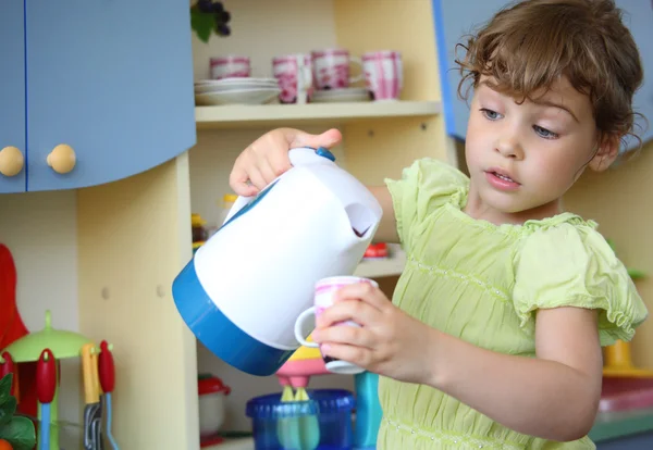 Маленька дівчинка з чайником і чашкою в руках — стокове фото