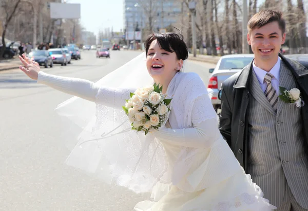 Nevěsta se snoubencem na ulici zastaví auto — Stock fotografie