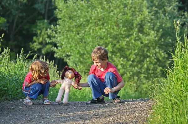 Children with doll on path in park — Stock Photo, Image