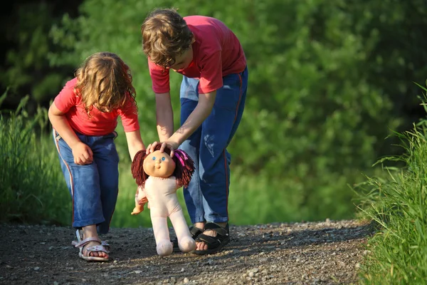 Junge und Mädchen gehen mit Puppe im Park spazieren — Stockfoto