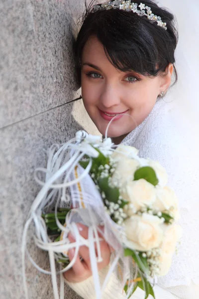 Невеста с букетом у стены — стоковое фото