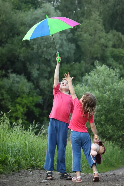 En parque chico sostiene paraguas sobre la cabeza, chica tira de ella mano — Foto de Stock