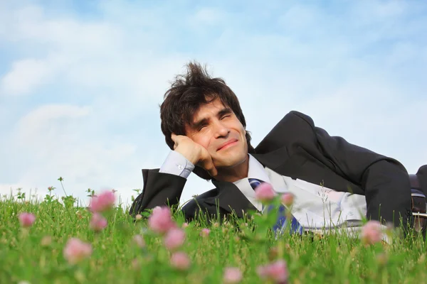 Бизнесмен лежит на траве с одной стороны с закрытыми глазами — стоковое фото