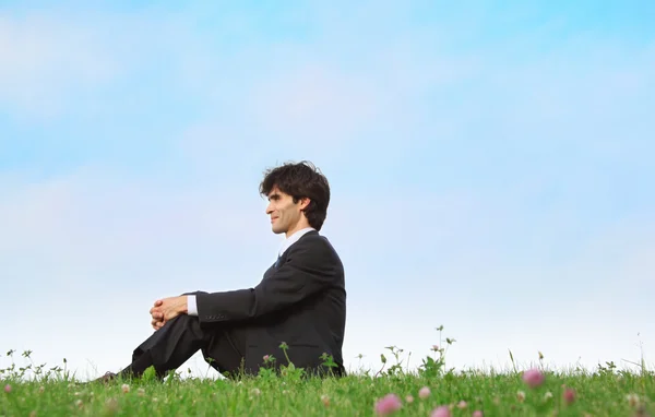 Uomo d'affari si siede sull'erba, vista di profilo — Foto Stock