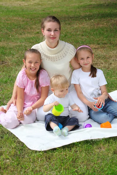 Mother with children sits on laying on grass — Stock Photo, Image