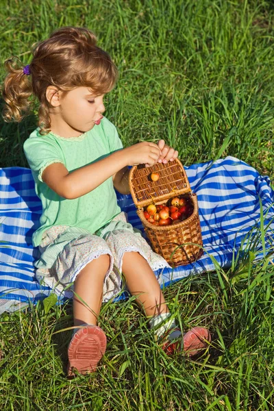Красива дівчинка отримає з кошика солодкі вишні в саду — стокове фото