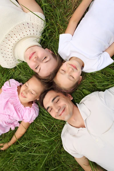 Parents with children lying on grass, view from top, head to hea — Stock Photo, Image